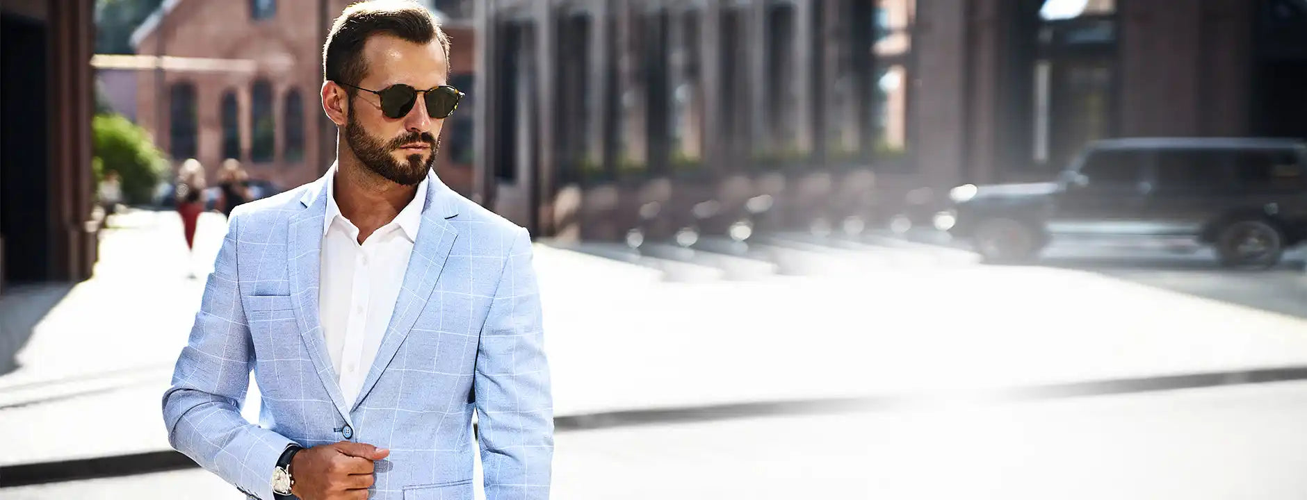 Uomo elegante con blazer a quadri azzurro chiaro e occhiali da sole